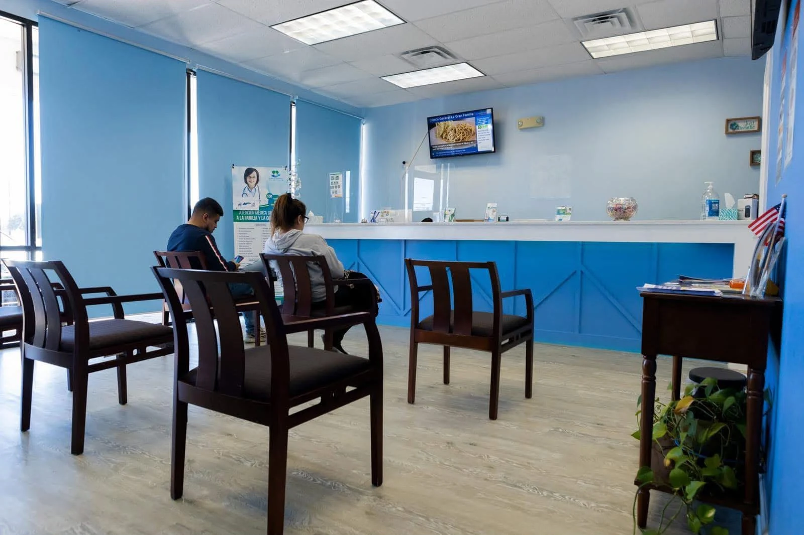 Mostrador de recepción de la clínica con pacientes esperando