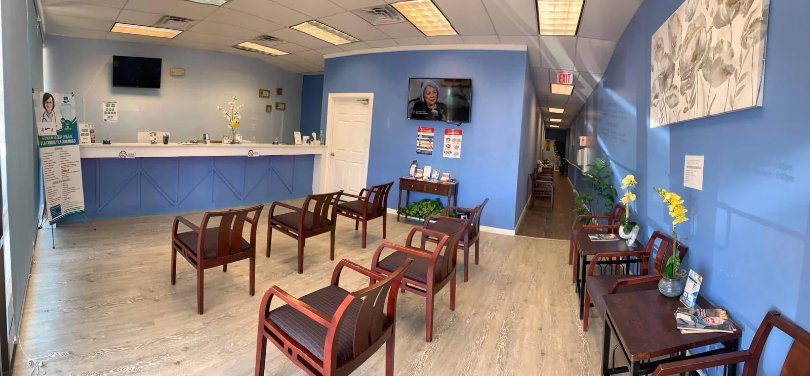 Sala de espera con butacas de madera y el mostrador al fondo